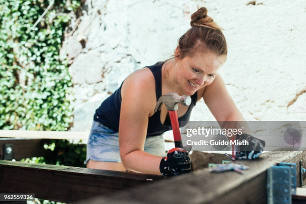 happy woman nailing, doing diy project outdoor. - guido mieth 個照片及圖片檔