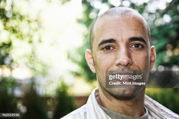 hispanic man in the backyard of his home. - shaved head stock pictures, royalty-free photos & images