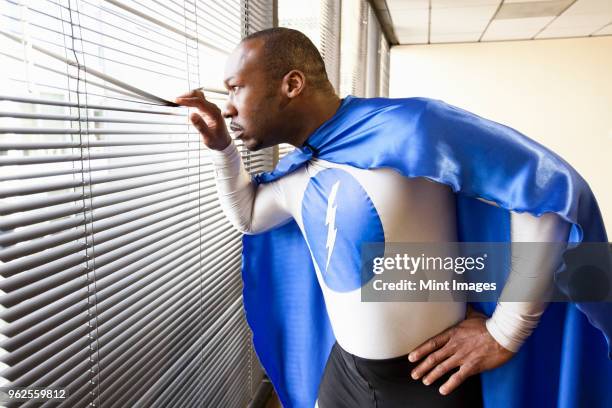a black businessman office super hero looks out the window and checks his next business move. - se déguiser photos et images de collection