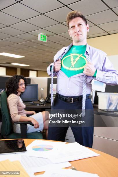 a caucasian man office super hero gets ready for action in his office. - red shirt stockfoto's en -beelden