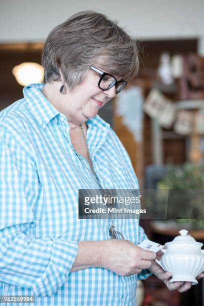 a caucasian woman checking out an item in an antique store. - antique shop stockfoto's en -beelden