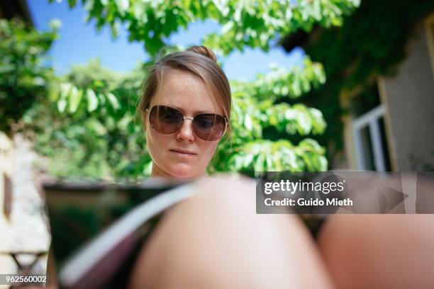 woman with sunglasses reading outdoor. - guido mieth stock-fotos und bilder