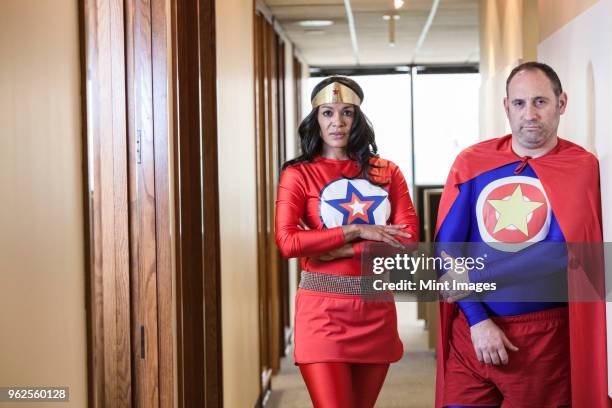 super hero office team made up of a black woman and a middle aged caucasian man. - men costume black and white stock-fotos und bilder