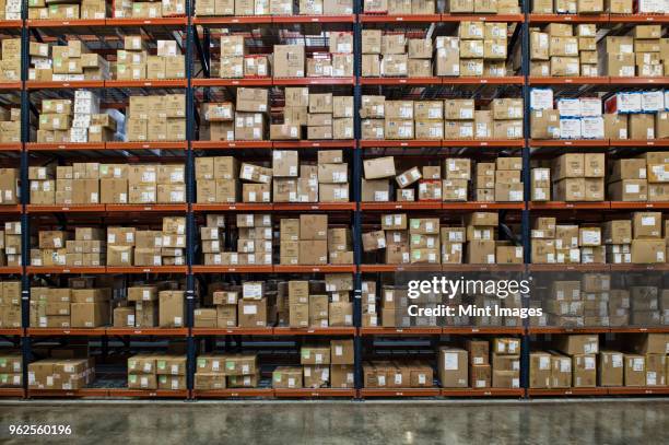 view of racks of cardboard boxes containing product in a large distribution warehouse. - package stock pictures, royalty-free photos & images