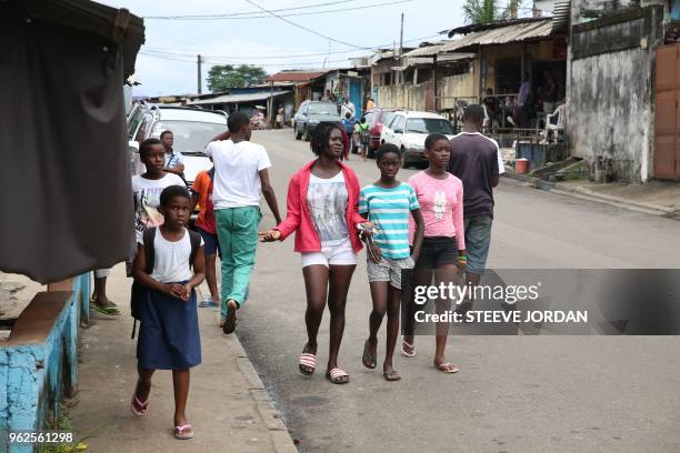 Young people walk in the street of the popular district of Kinguele, in Libreville on May 24, 2018. - The "tolibangando" slang used in the popular...