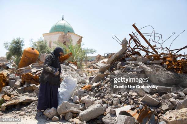 April 24: A veiled woman searches for and collects usable material at the destroyed Al Nuori Mosque in the old city in Mosul on April 24, 2018 in...