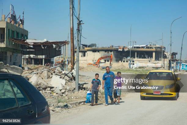 April 24: A father walks with his two sons on a street in the destroyed old town in Mosul on April 24, 2018 in MOSUL, IRAQ.