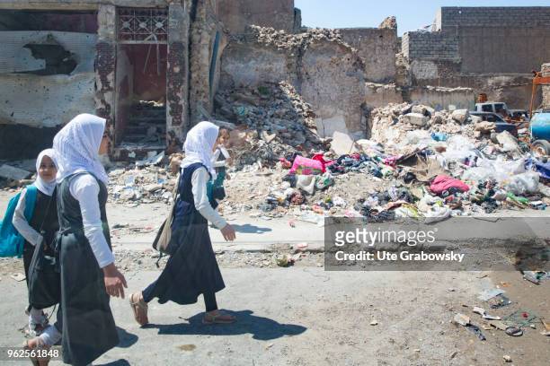 April 24: Girls in school uniforms walk on a street passing ruined houses in the destroyed old town in Mosul on April 24, 2018 in MOSUL, IRAQ.