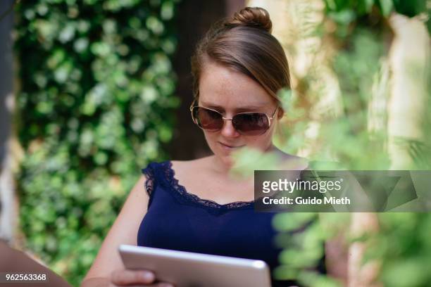 woman with sunglasses using tablet pc. - guido mieth stock-fotos und bilder