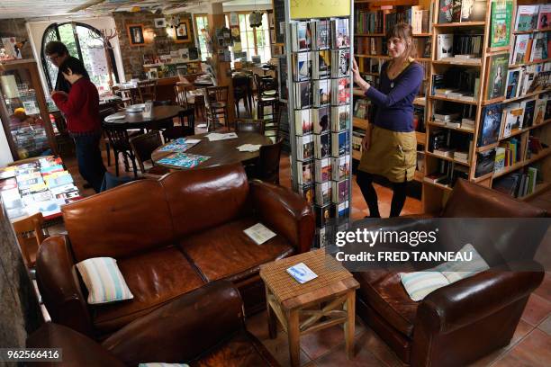 Costumer looks at books displayed in the coffee-bookshop "L'autre Rive" in Berrien, western France on May 2, 2018. - The trend of the...