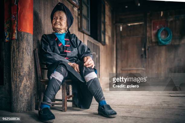 old minority chinese woman sitting on stool indoors - yao tribe stock pictures, royalty-free photos & images
