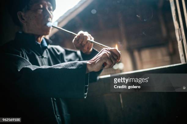 old minority chinese man smoking pipe at window - yao tribe stock pictures, royalty-free photos & images