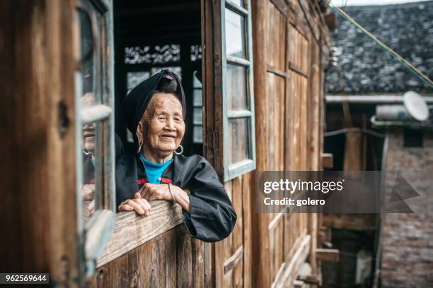 old minority chinese woman looking out of window - yao tribe stock pictures, royalty-free photos & images