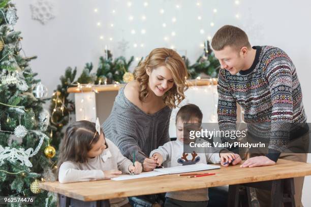 man looking at woman and children drawing in book on table at home - pindyurin stock-fotos und bilder