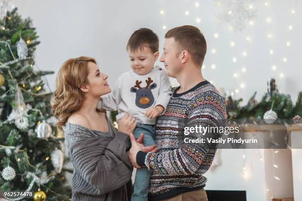 father and mother carrying son at home during christmas - pindyurin foto e immagini stock