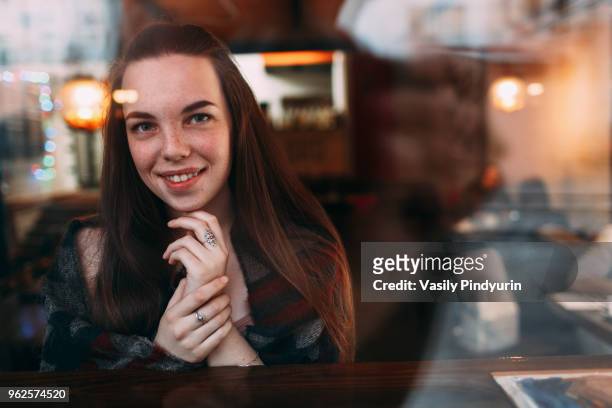smiling beautiful young woman seen through cafe window - pindyurin foto e immagini stock