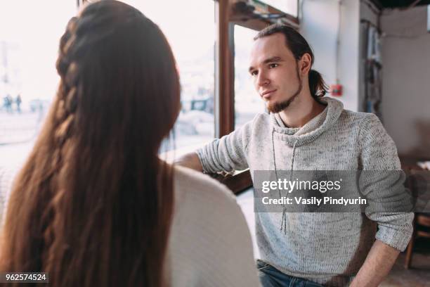 young couple sitting by window at cafe - pindyurin foto e immagini stock