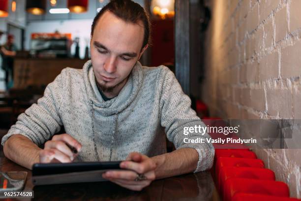 young man using digital tablet at cafe - pindyurin foto e immagini stock