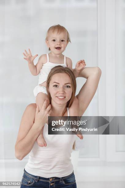 portrait of happy mother carrying daughter on shoulders at home - pindyurin stock-fotos und bilder