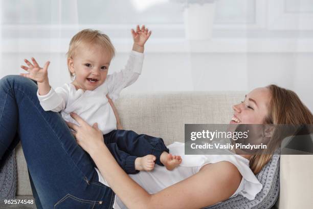 happy mother and daughter enjoying on sofa at home - pindyurin stock-fotos und bilder