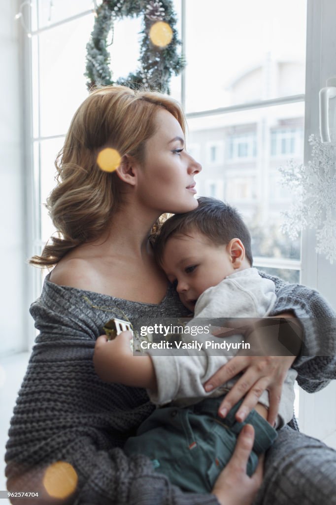 Young woman sitting with son by window at home