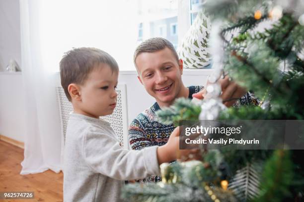 happy father and son decorating christmas tree at home - pindyurin foto e immagini stock