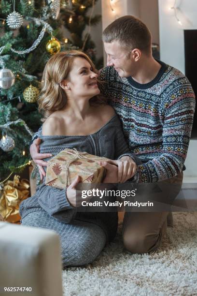 happy couple with present by christmas tree at home - pindyurin foto e immagini stock