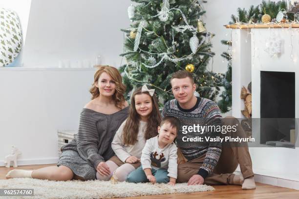 portrait of happy family sitting against christmas tree - pindyurin foto e immagini stock