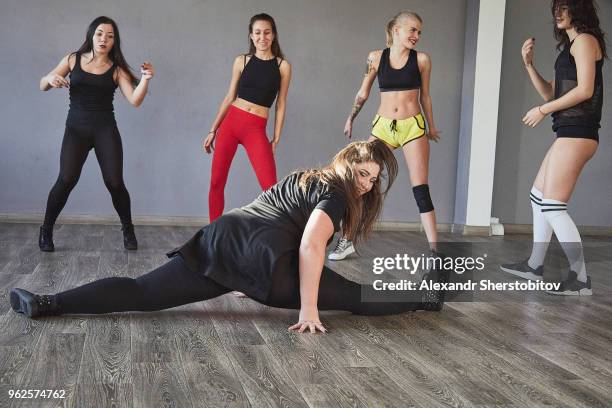 young woman doing splits while friends dancing at studio - fat woman dancing stockfoto's en -beelden
