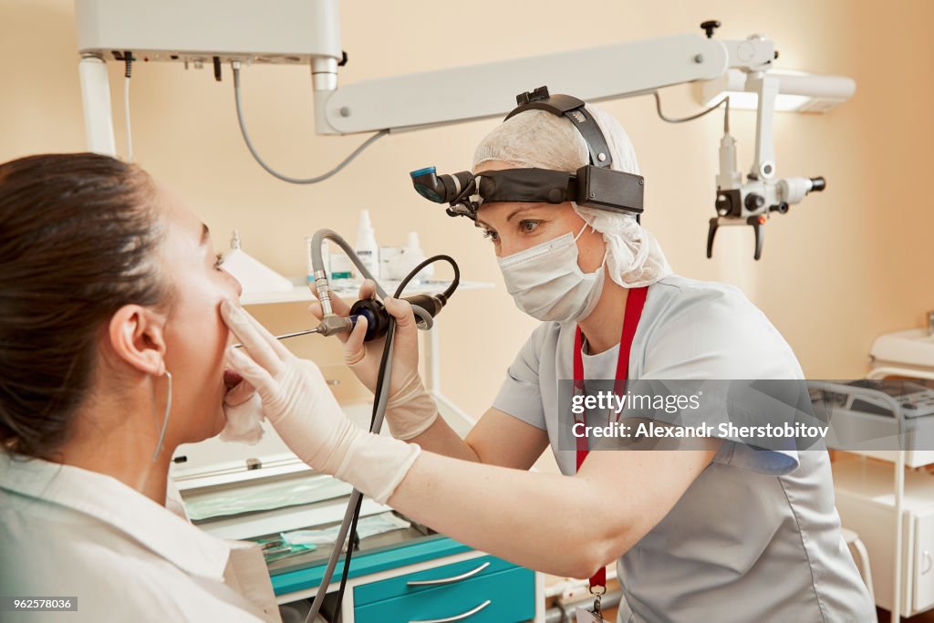 Doctor using equipment while examining female patient at hospital