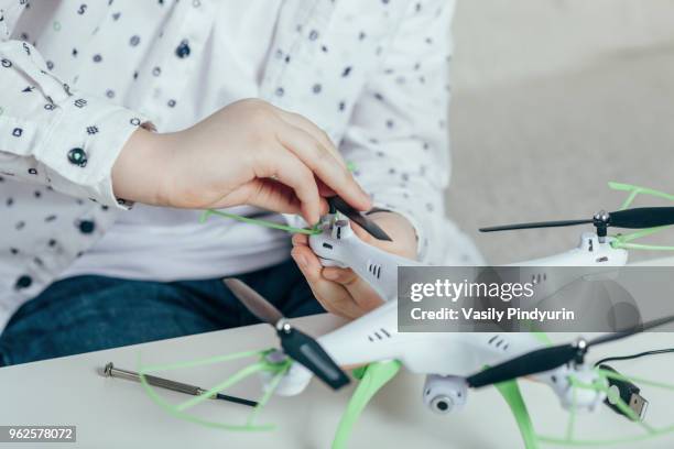 midsection of boy adjusting drone at home - pindyurin stock-fotos und bilder