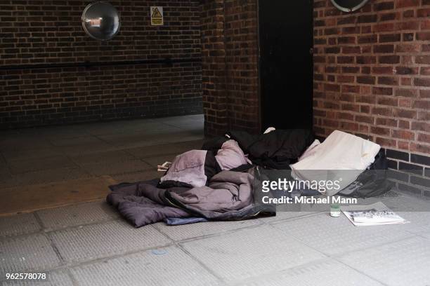 high angle view of sleeping bag on footpath by brick wall in city - homelessness stock pictures, royalty-free photos & images