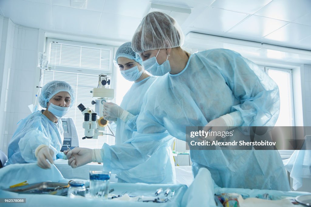 Female surgeon passing medical equipment to doctor during surgery at hospital