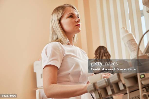 nurse using monitoring equipment during medical procedure at hospital - sherstobitov stock pictures, royalty-free photos & images