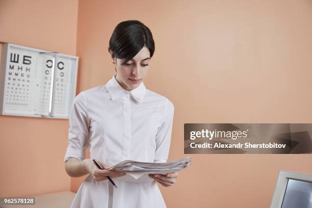 nurse reading papers while standing in hospital - sherstobitov stock pictures, royalty-free photos & images