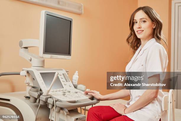 portrait of smiling confident doctor sitting by ultrasound machine at hospital - sherstobitov stock pictures, royalty-free photos & images