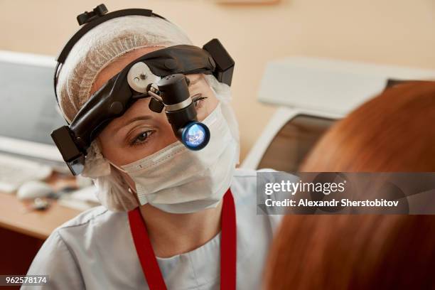 surgeon wearing headlamp while examining female patient at hospital - sherstobitov stock pictures, royalty-free photos & images