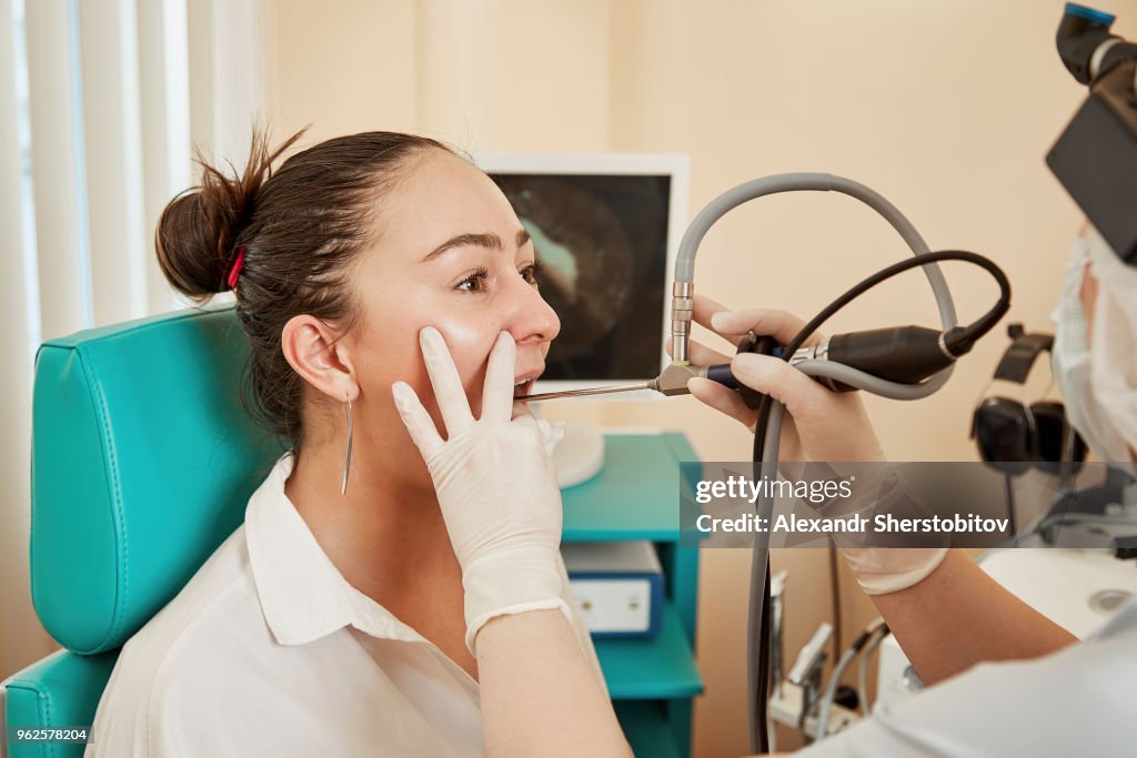 Cropped image of doctor using equipment while examining patient's mouth at hospital