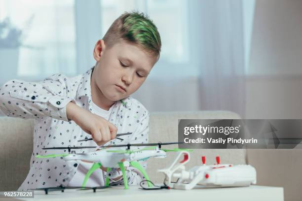 confident boy adjusting drone on coffee table while sitting at home - pindyurin stock-fotos und bilder