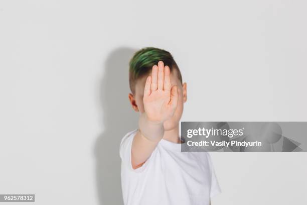 boy showing stop sign while standing against white background - pindyurin stock-fotos und bilder