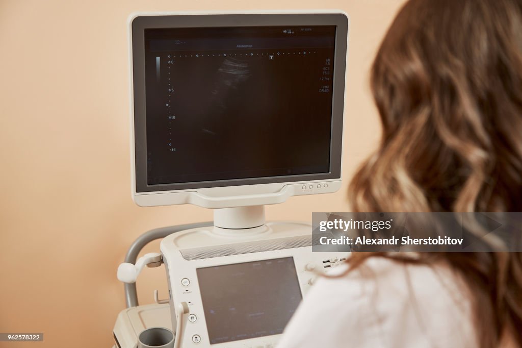 Rear view of medical worker using ultrasound machine at hospital