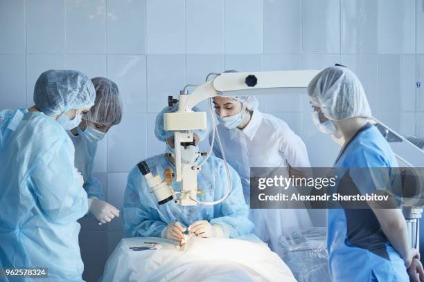 medical team performing surgery on patient at hospital - sherstobitov stock pictures, royalty-free photos & images