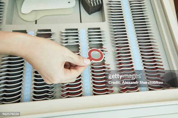cropped image of doctor holding lens from rack during eye test - sherstobitov stock pictures, royalty-free photos & images