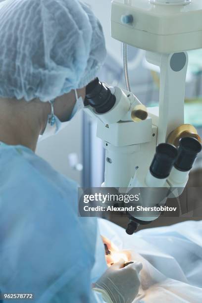 surgeon using machinery during eye surgery - micro surgery stock pictures, royalty-free photos & images