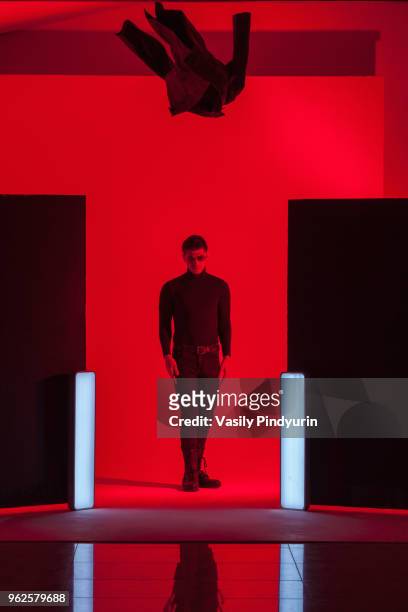 full length of young man standing below falling jacket amidst illuminated lights in red studio - photoshoot bts stock pictures, royalty-free photos & images