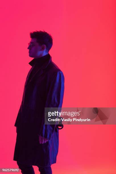 young male fashion model standing against coral background - pindyurin stock-fotos und bilder