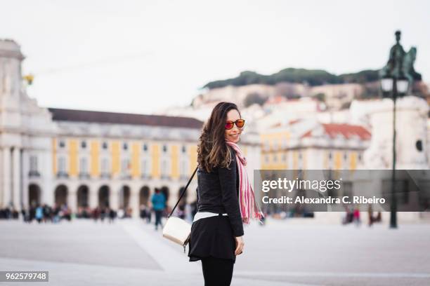 smiling mid adult woman standing at town square against building in city, lisbon, portugal - comercio stock-fotos und bilder