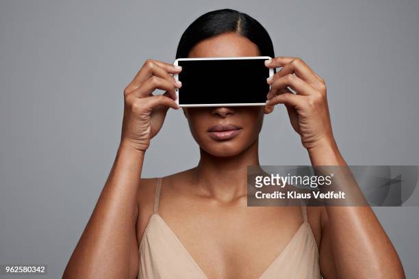 woman holding smartphone in front of her eyes - huidkleurig stockfoto's en -beelden