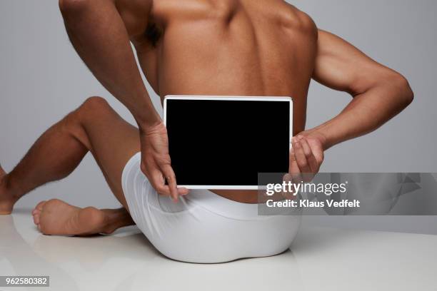 man holding tablet in front of his back - gluteos fotografías e imágenes de stock