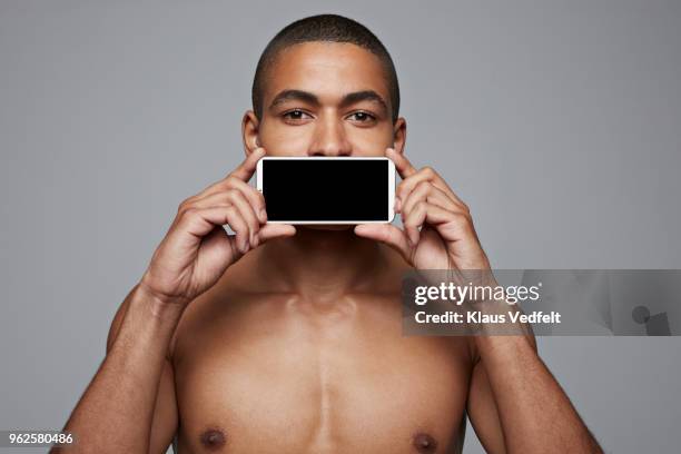 man holding smartphone in front of his mouth - obscured face stock pictures, royalty-free photos & images